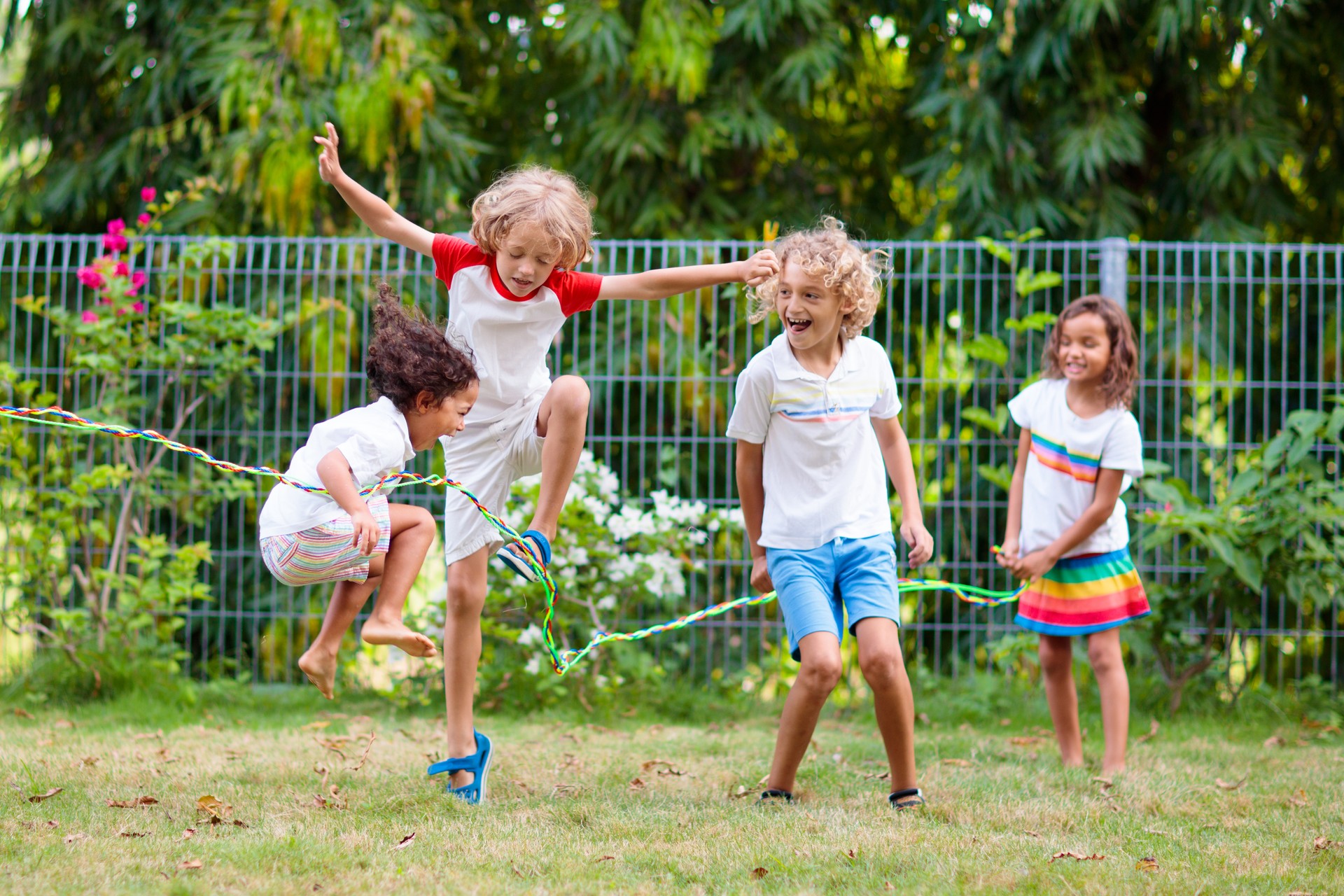 Happy kids play outdoor. Children skipping rope.